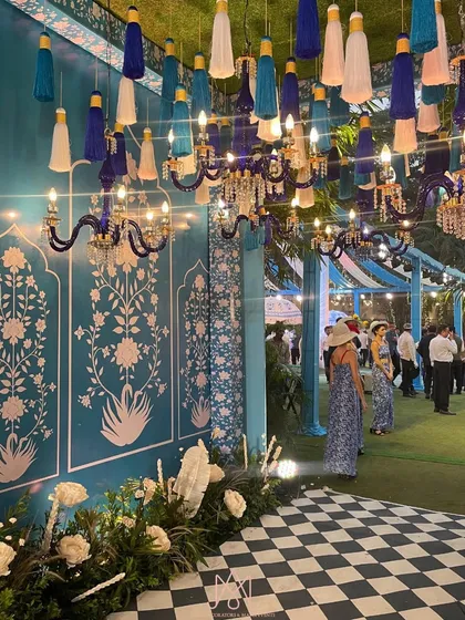 The entrance to the Moroccan-themed event, where guests are greeted by a stunning wall with blue and white prints, checkered flooring, and hanging tassels.