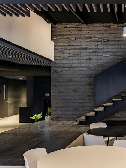 Another view of the work lounge at BCG HQ, showing how the dark, textured brick wall and staircase create a sophisticated and grounded atmosphere.