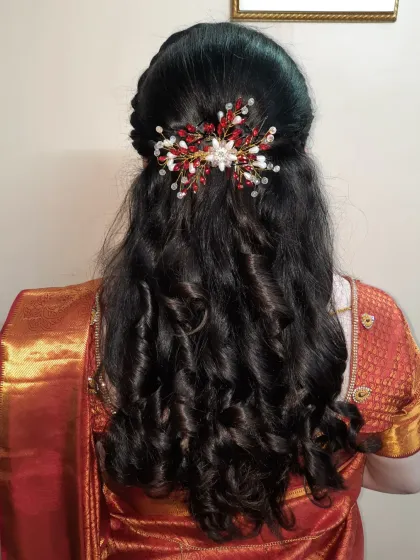 Soft, bouncy curls styled in a half-updo with a beautiful red and white beaded hair accessory. This is a perfect look for a party or reception.