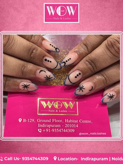 Celestial-themed nail art on long, almond-shaped extensions. This design features delicate stars and moons in black on a neutral base, creating a mystical and trendy look.