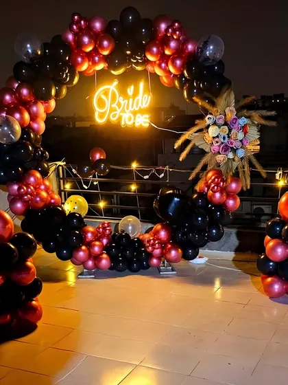 A clearer view of the rooftop "Bride to be" decor at night. The lighting highlights the rich colors of the balloons and the dried floral arrangement on the arch.
