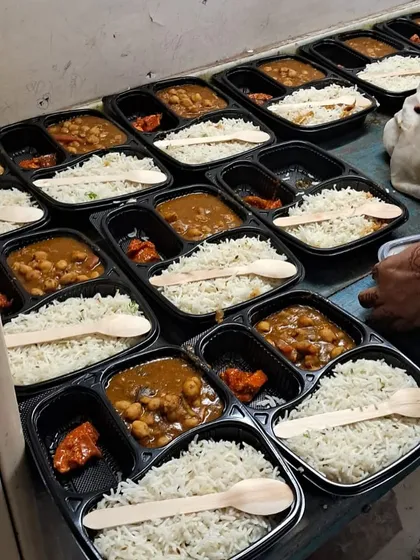 Rows of Chole and Rice thalis being prepared. We also include a side of pickle and provide eco-friendly wooden spoons.