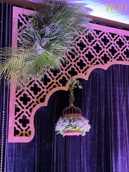 A close-up of the hanging birdcage filled with white flowers, a unique and charming detail for a sangeet or reception stage.