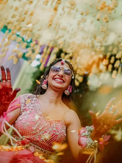 A beautiful, artistic shot of the bride with her henna-covered hands, seen through a shower of flower petals.