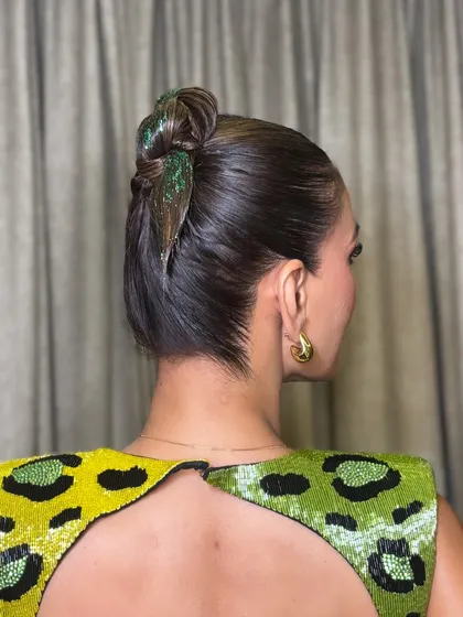 A side view of the glittery high bun. You can see how the hair is slicked back for a clean finish, making the green glitter and the twisted bun the main focus of the style.