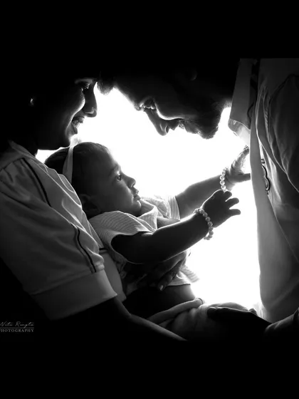 A close-up black and white silhouette capturing the bond between parents and child. The focus is purely on their expressions and connection.