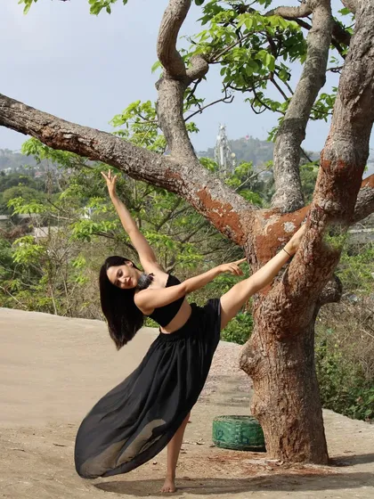 In my element. Using a tree as a prop to deepen my standing split, connecting with the strength and support of nature.