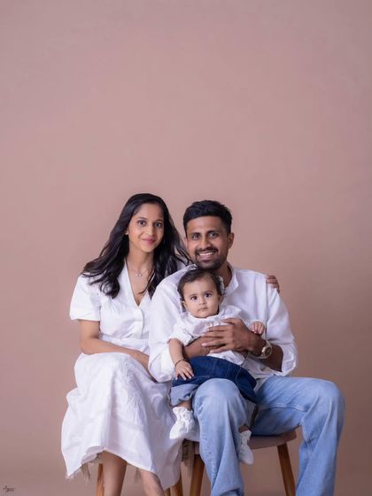 A classic seated family portrait. The family looks directly at the camera, creating a beautiful, timeless photograph to hang on the wall. The simple backdrop and coordinated outfits give it a clean, modern feel.
