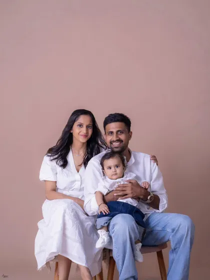 A classic seated family portrait. The family looks directly at the camera, creating a beautiful, timeless photograph to hang on the wall. The simple backdrop and coordinated outfits give it a clean, modern feel.