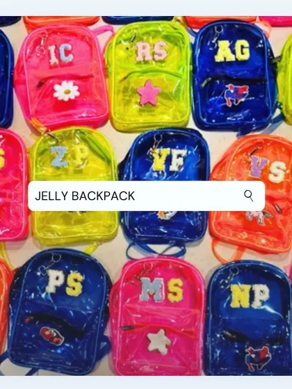 A large collection of our custom jelly backpacks, prepared as return favors. This image shows the variety of neon colors and initial personalizations that make each bag unique.