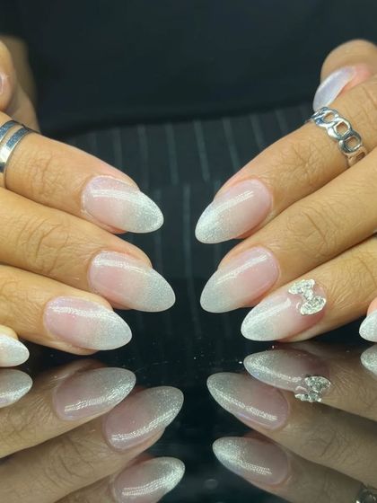 A beautiful cat-eye manicure with a silvery-white shimmer, accented with a 3D rhinestone bow.