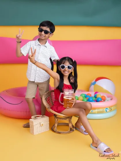 Peace out! These siblings are having a blast at their studio beach party. Themed shoots are a great way to capture sibling fun.