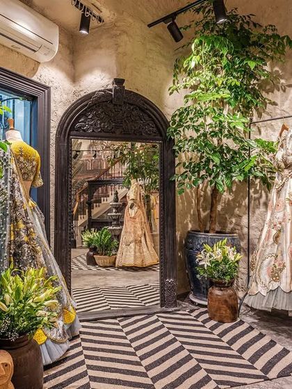 The strategic use of mirrors and greenery creates depth and a sense of lushness within the store. The arched mirror reflects the boutique's interior, making the space feel larger and more immersive for shoppers.