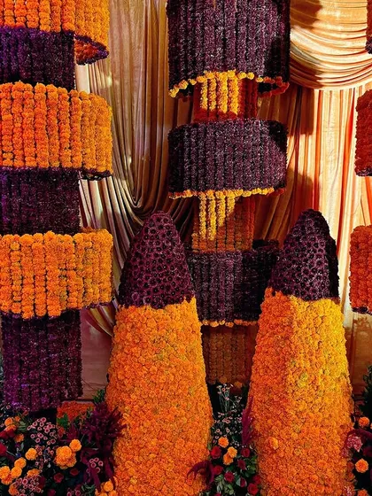 A massive, multi-tiered structure made entirely of orange and purple marigolds, creating a stunning and modern backdrop for a Diwali party.