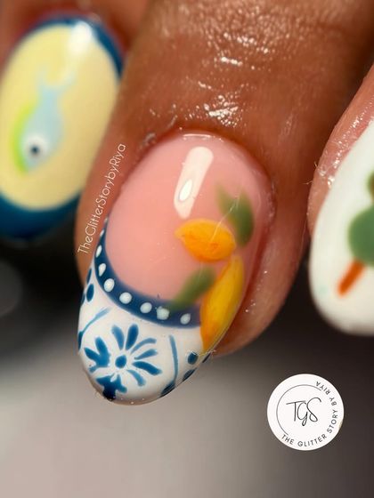A close-up of a hand-painted nail inspired by Italian summer, featuring a lemon design on a Portuguese tile-style base.