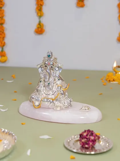 A serene Ganesha idol resting on a polished rose quartz base. The combination of shimmering silver and the gentle pink of the stone creates a calming and loving energy, ideal for a peaceful corner of your home.