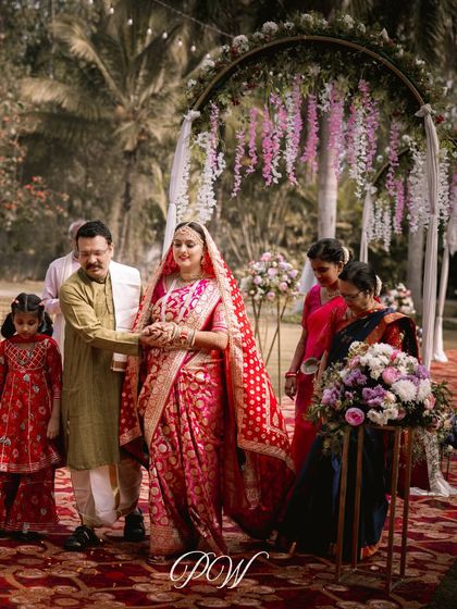The bride's entrance during her wedding ceremony, walking down an aisle lined with beautiful floral arrangements.