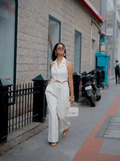 A duplicate of image 318, this full-length shot of a model in a chic white outfit, walking down a city street, captures a natural, candid moment of urban style.