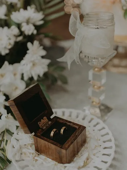An aesthetic shot of the engagement rings nestled in their box, placed on a decorative plate with flowers.