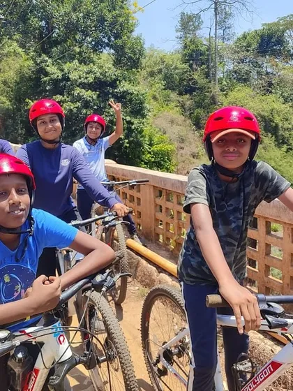A team of young cyclists in red helmets pauses on a bridge during their ride, enjoying the view.