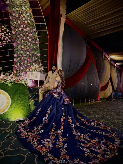 A romantic shot of our client and her husband on their reception night. Her navy floral ball gown spreads out around them, creating a fairytale scene. The intricate embroidery on the train is a testament to our detailed craftsmanship.