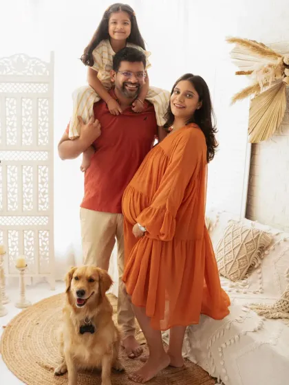 A beautiful maternity portrait of a family of four, including their beloved dog. The older daughter sits on her father's shoulders, adding a playful touch.