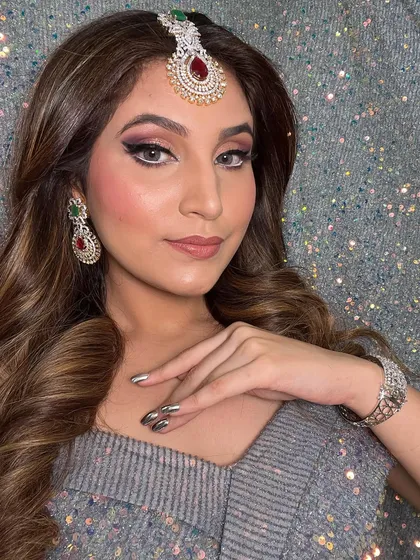 The client's complete party look, featuring soft waves, a statement maang tikka, and dramatic makeup. This is perfect for anyone who wants to stand out.