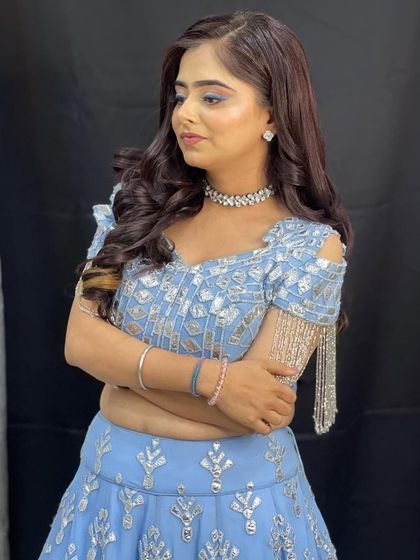 A close up of the powder blue lehenga, showing the unique shoulder design with hanging silver tassels.