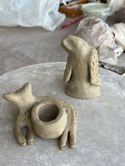A 'sitting cat' candle holder and a 'tired owl' figurine, waiting to be fired. I love sculpting these small, characterful creatures, each with its own personality.
