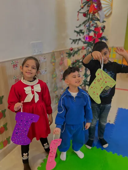Three friends proudly show off the Christmas stockings they decorated. It's wonderful to see their unique creativity and the pride they take in their work.