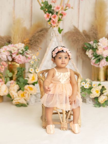 A lovely portrait in a boho-chic setting. The soft pastel colors, floral arrangements, and lace teepee create a gentle and beautiful atmosphere for a first birthday shoot.