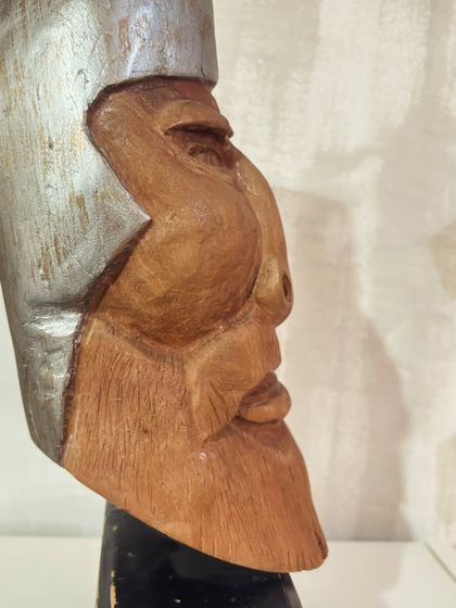 A profile view of our hand-carved wooden sculpture, showing the strong lines of the face and the texture of the beard, all shaped by hand.