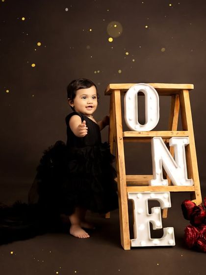 A glamorous first birthday shoot featuring a stunning black tulle dress and light-up 'ONE' letters. This theme creates dramatic and elegant portraits.
