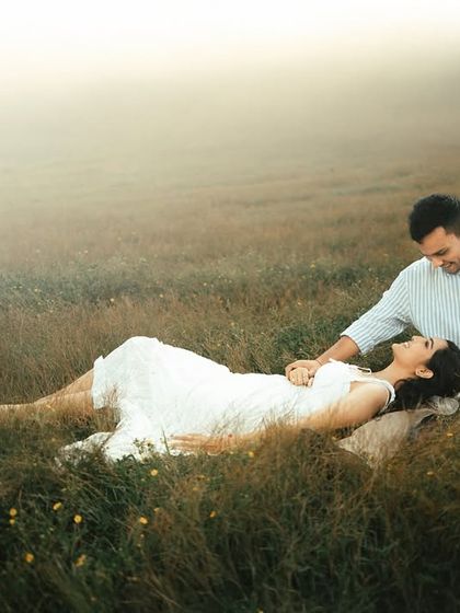 A tender moment shared in a field of tall grass, enveloped in a soft morning mist. This intimate couple portrait focuses on their quiet connection, creating a photograph that feels both personal and serene.