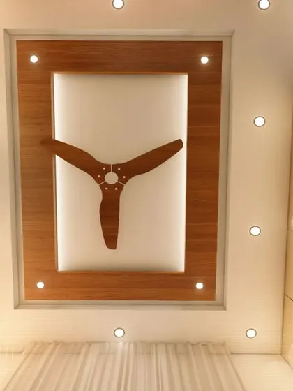 A view of the bedroom's false ceiling, which features a wooden panel and recessed spotlights, complementing the room's warm and modern theme.