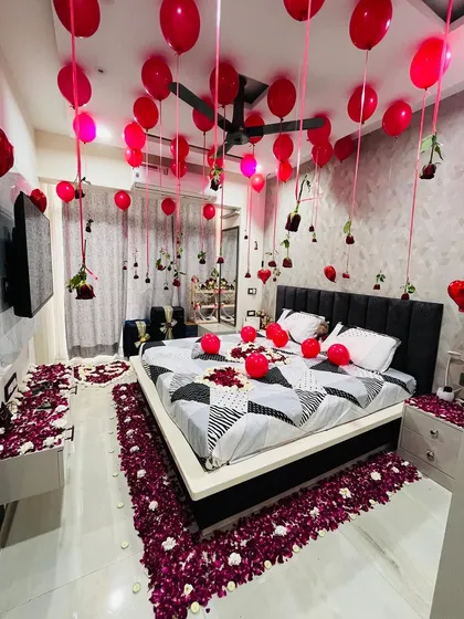 This angle shows how the entire room comes together to create a cohesive and immersive romantic environment. The combination of the balloon ceiling, the petal-strewn floor, and the decorated bed ensures that from the moment you walk in, the mood is set for a celebration of love.