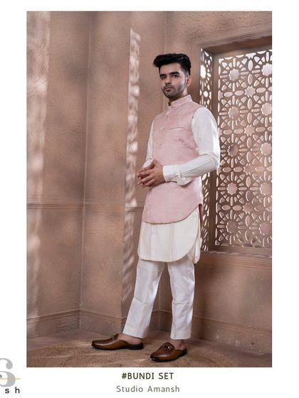 The rose pink bundi set, shown against a textured backdrop. The soft pastel tone is ideal for daytime celebrations and summer weddings, offering a sophisticated and stylish option.