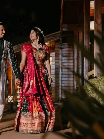 Another angle of the couple's night-time walk, capturing their elegant traditional ensembles in a festive setting.