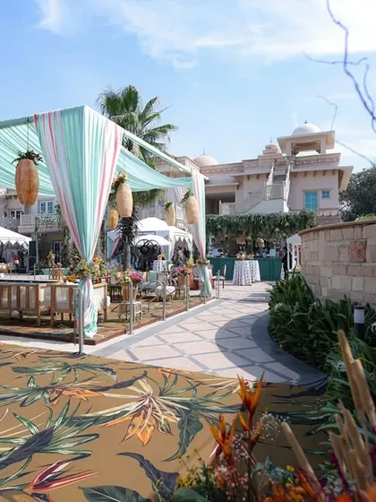 Another view of the tropical-themed event, with a printed carpet leading to a bar area draped in aqua fabric.