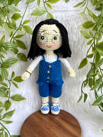 A lovely replica doll in a blue jumpsuit with matching shoes. The details, like her glasses and hairstyle, were carefully crafted to match the photos provided. These dolls can be made to stand on a wooden base.
