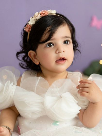 A portrait of the baby girl looking curious during her whimsical first birthday photoshoot.