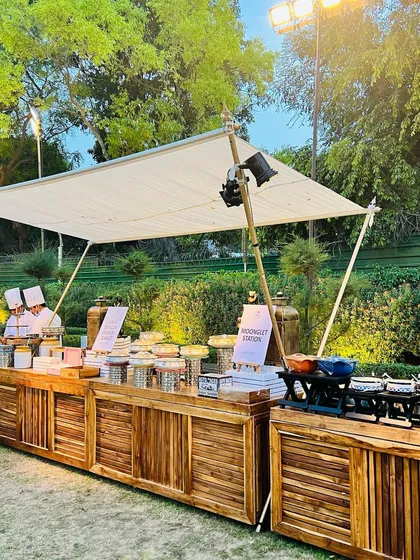 This rustic wooden buffet station was designed for an elegant outdoor event. The clean lines, professional chef service, and clear signage for each food station ensure a sophisticated and organized dining experience for all guests.