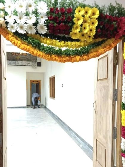 A housewarming flower decoration for a door. The arch is made of colorful gerberas, roses, and other fresh flowers for a vibrant look.