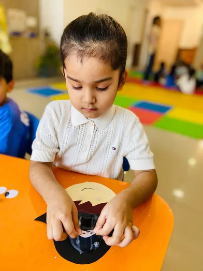 This little girl is carefully assembling her craft, showing her intense focus and developing dexterity.