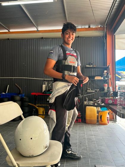 A driver takes a break between sessions during his international debut at the RMC Asia Trophy, smiling after a strong performance.