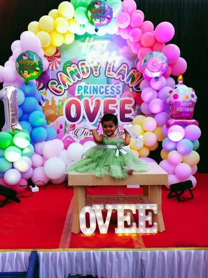 The birthday girl enjoying her vibrant Candy Land themed party, complete with marquee letters spelling her name.