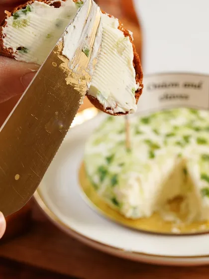 A satisfying close-up of the creamy onion and chives spread being applied to a cracker, highlighting its texture.