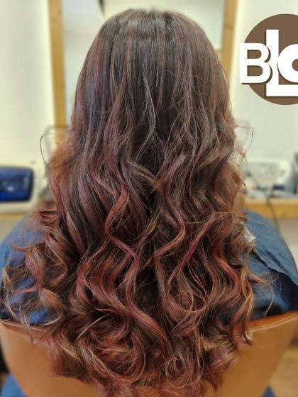 Soft curls showcasing a beautiful blend of red and brown tones. This color combination adds warmth and richness to the hair.