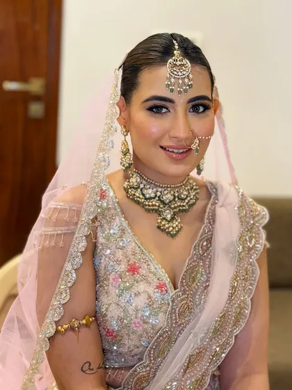 A smiling portrait of the bride. Her makeup is flawless, and her jewelry perfectly complements the pastel outfit.