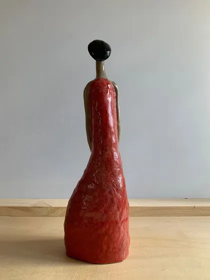 The back of the 'Damn Red Woman' sculpture, showing the smooth, vibrant red glaze.